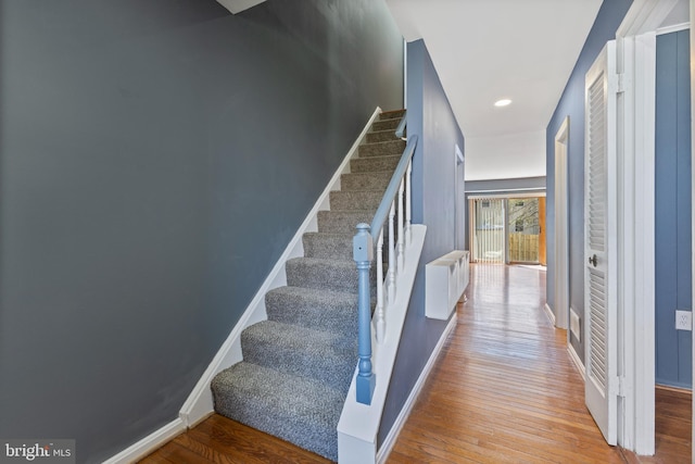 stairway with radiator heating unit, baseboards, wood finished floors, and recessed lighting