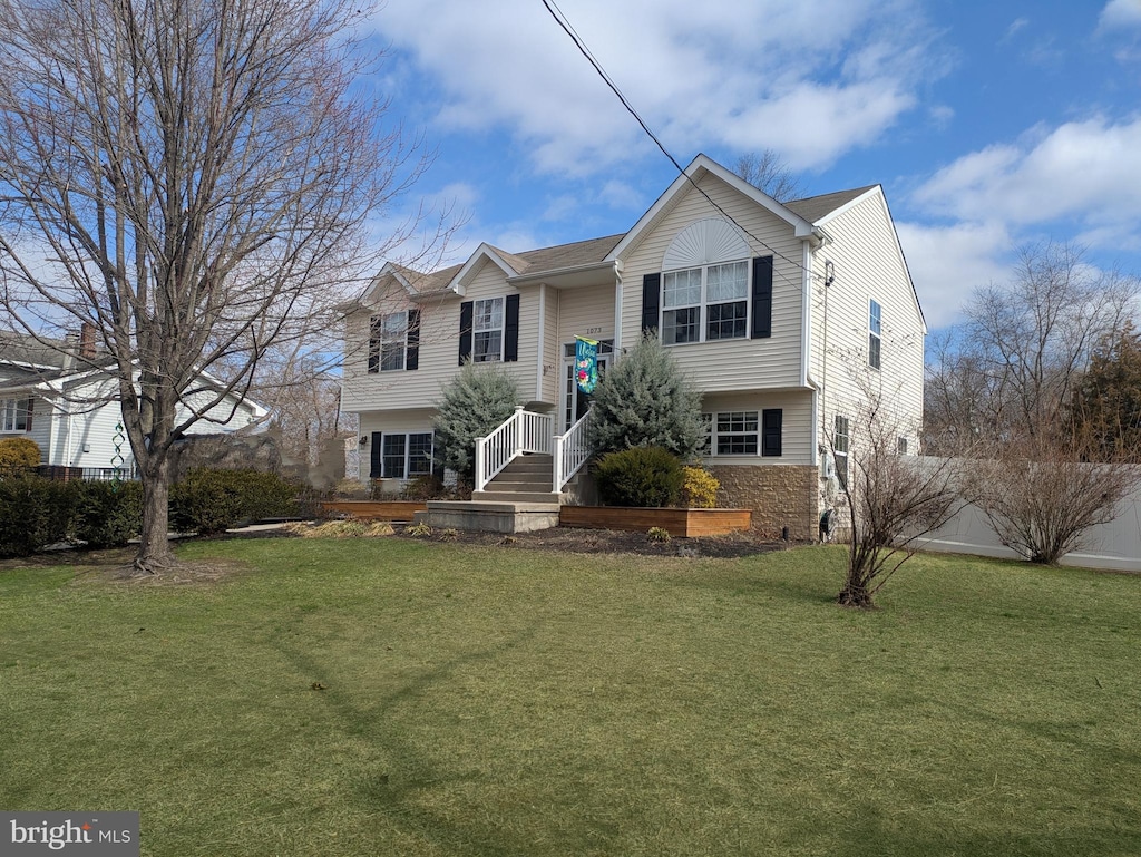 split foyer home featuring stone siding and a front lawn