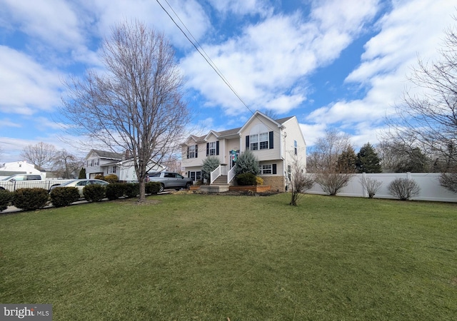 view of front of house featuring a front yard, stone siding, and fence