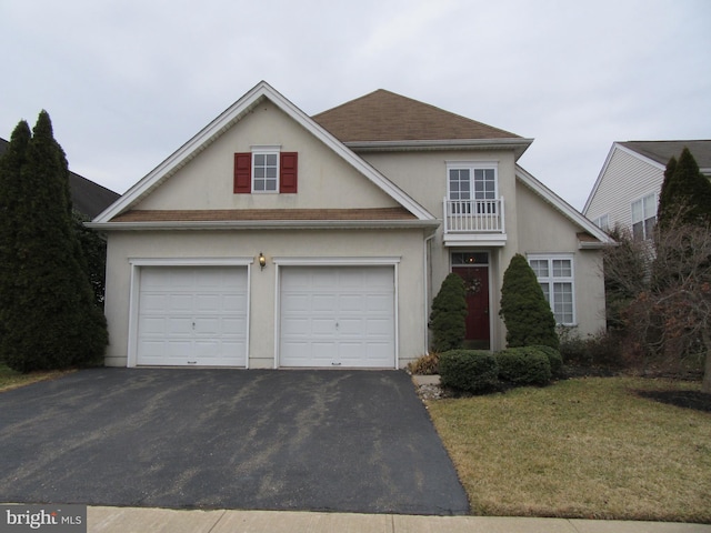 traditional home featuring aphalt driveway, a front yard, a shingled roof, and stucco siding