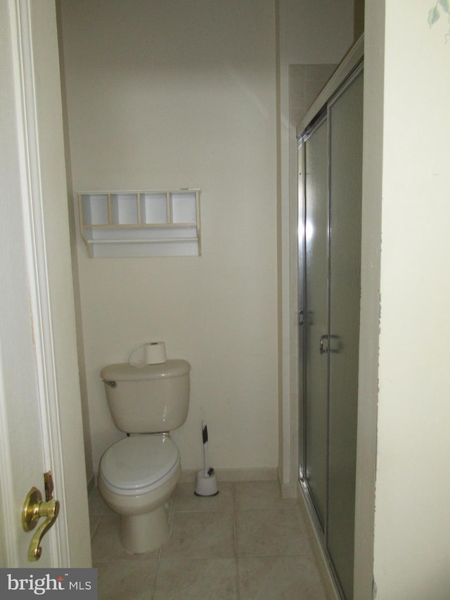 full bathroom featuring toilet, a stall shower, baseboards, and tile patterned floors