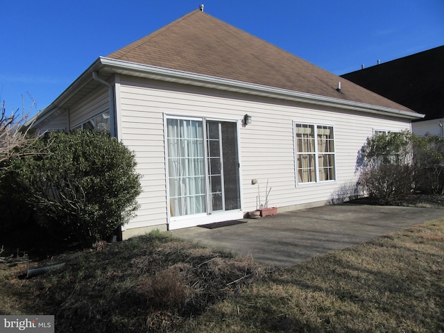 back of house featuring roof with shingles and a patio