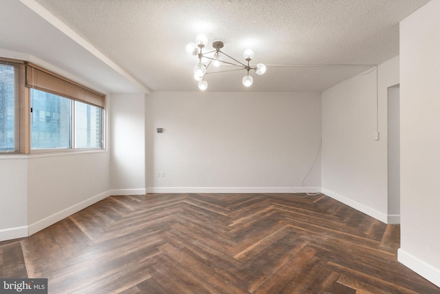 spare room featuring baseboards, a textured ceiling, and an inviting chandelier