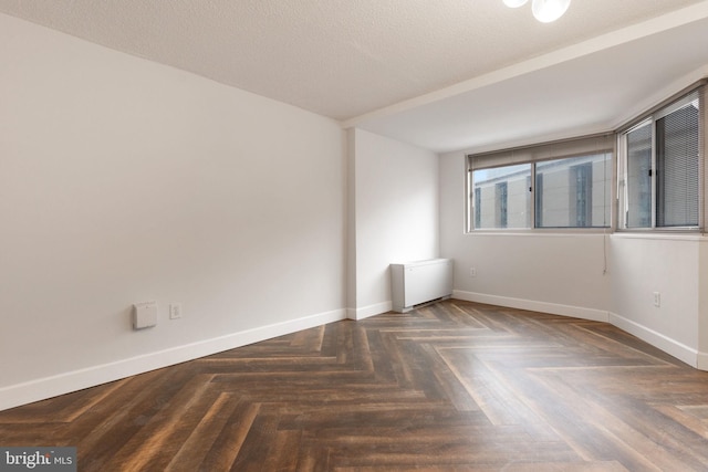 empty room with a textured ceiling and baseboards