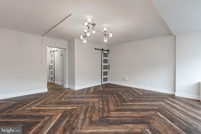 unfurnished room with baseboards, a barn door, a textured ceiling, and an inviting chandelier