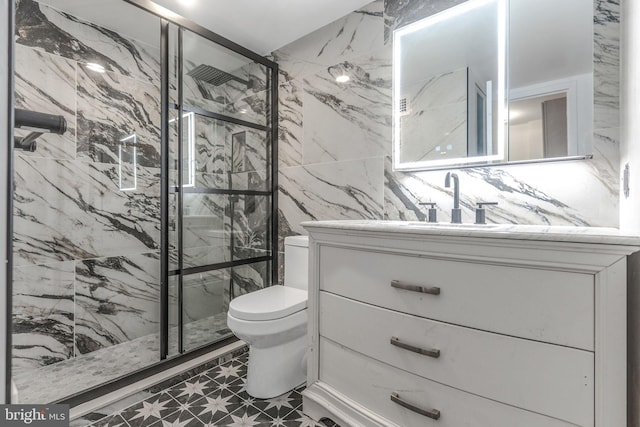 full bath featuring vanity, a marble finish shower, toilet, and tile walls