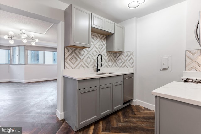 kitchen with baseboards, a sink, light stone countertops, gray cabinetry, and backsplash