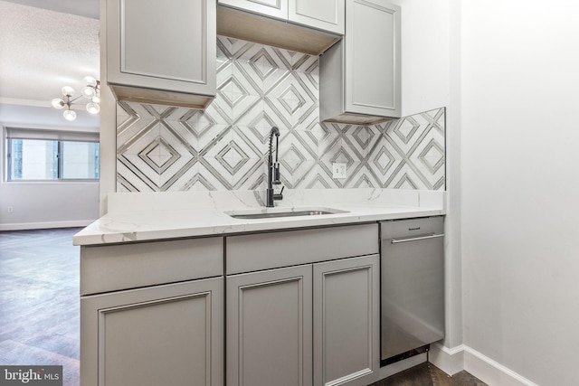 kitchen with a sink, baseboards, gray cabinets, decorative backsplash, and dishwasher