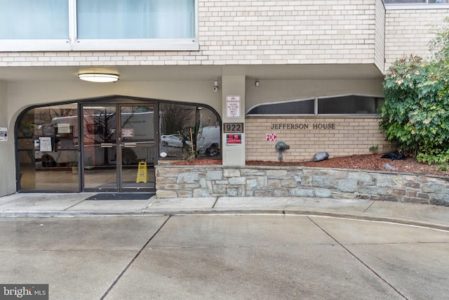 view of exterior entry with brick siding and stucco siding