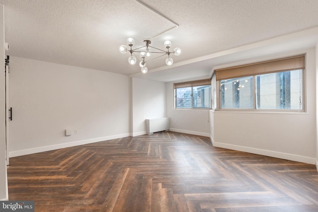 spare room featuring a textured ceiling, baseboards, and a notable chandelier