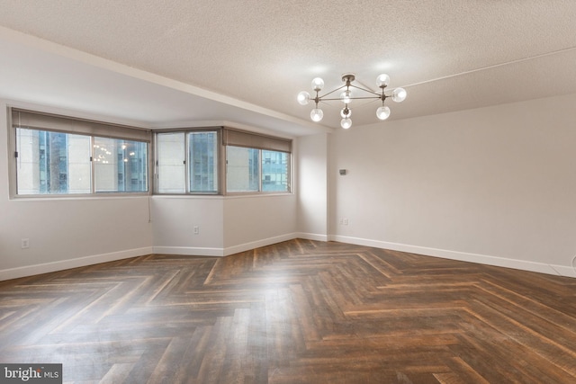 spare room featuring baseboards, a textured ceiling, and an inviting chandelier