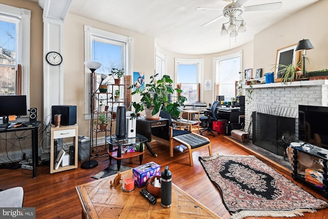 living room featuring ceiling fan, a fireplace, and wood finished floors