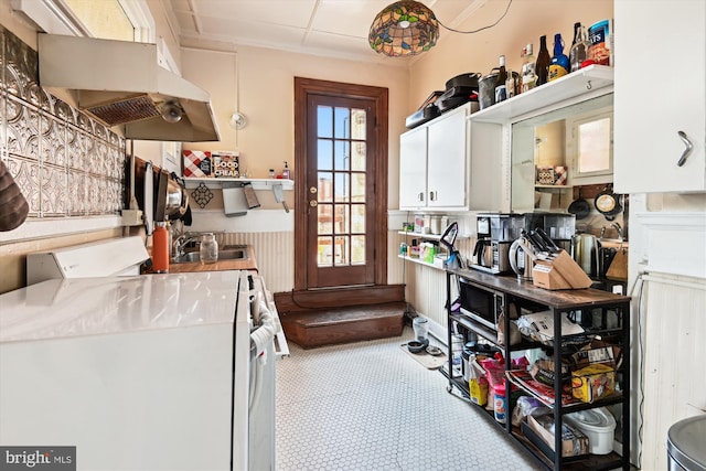 interior space with white cabinets, range with gas cooktop, under cabinet range hood, open shelves, and a sink