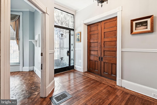 entrance foyer featuring wood-type flooring, visible vents, baseboards, and ornamental molding