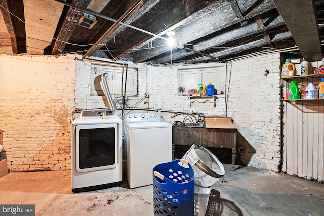 washroom featuring laundry area, washer and clothes dryer, and brick wall