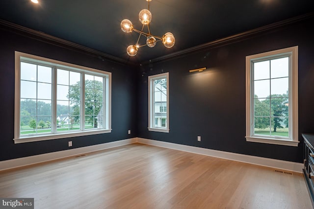 spare room featuring light wood finished floors, visible vents, baseboards, crown molding, and a notable chandelier