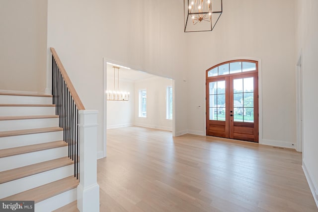 entrance foyer with a chandelier, stairway, plenty of natural light, and light wood-style floors