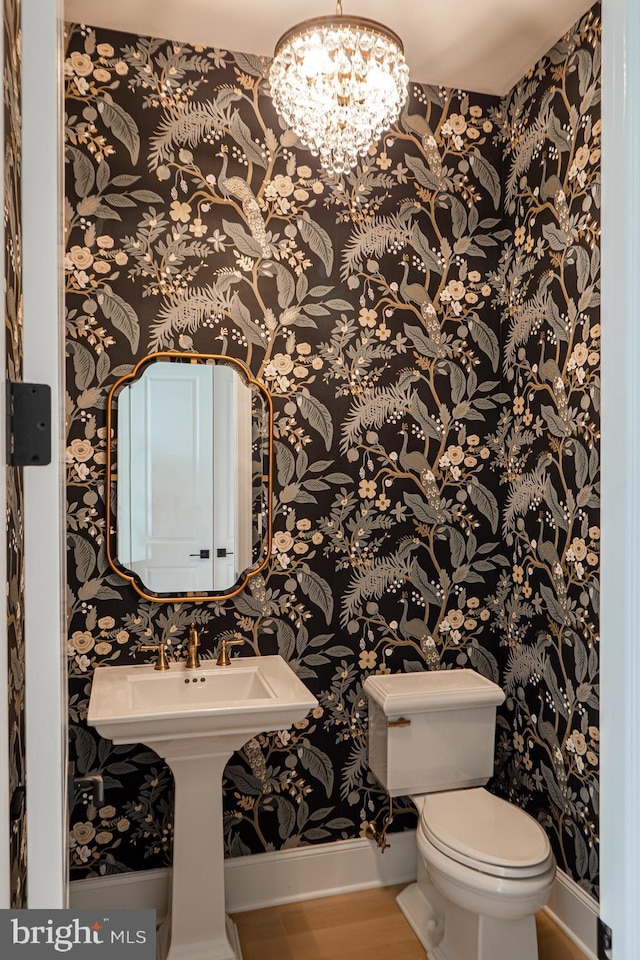 half bath with a notable chandelier, wallpapered walls, toilet, and baseboards