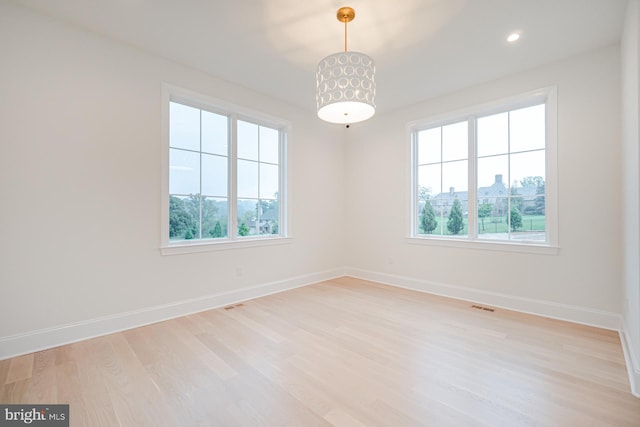 unfurnished room with light wood-type flooring, visible vents, baseboards, and a wealth of natural light