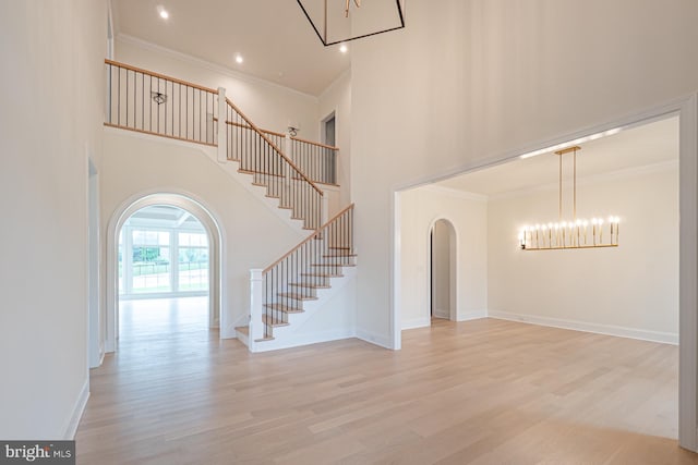 interior space with baseboards, arched walkways, a towering ceiling, stairway, and wood finished floors