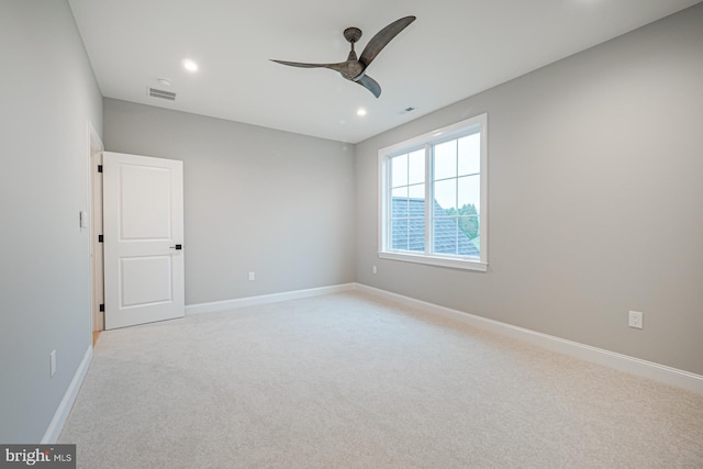 empty room with light colored carpet, visible vents, ceiling fan, and baseboards