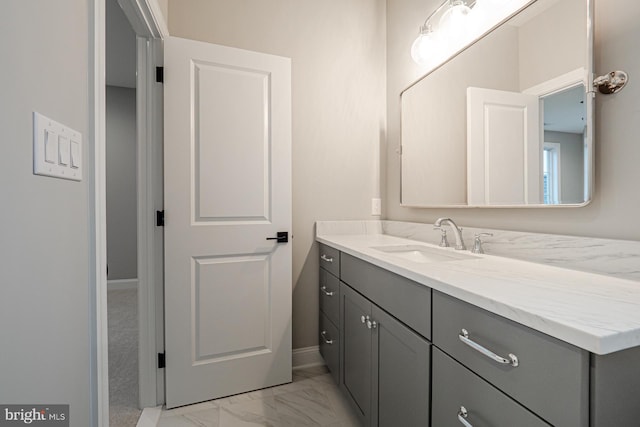 bathroom with marble finish floor, vanity, and baseboards