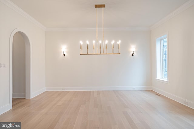 spare room featuring light wood-style floors, arched walkways, ornamental molding, and baseboards