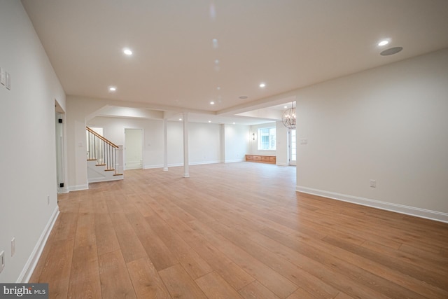 unfurnished living room with recessed lighting, light wood-style flooring, an inviting chandelier, baseboards, and stairs