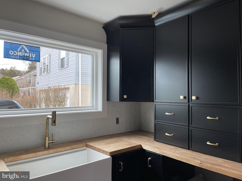 interior space featuring a sink, butcher block countertops, and dark cabinetry