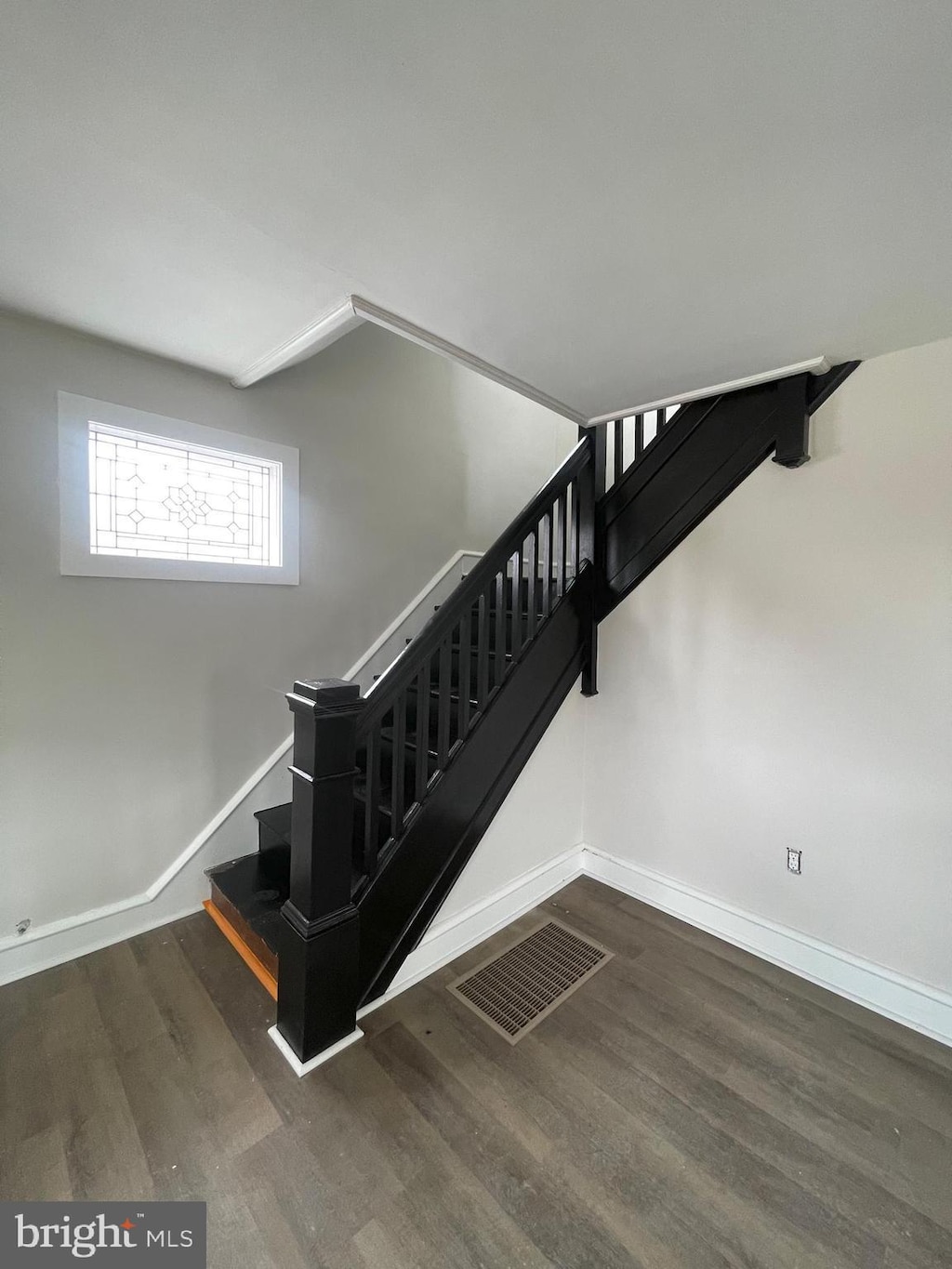 stairway featuring visible vents, baseboards, and wood finished floors