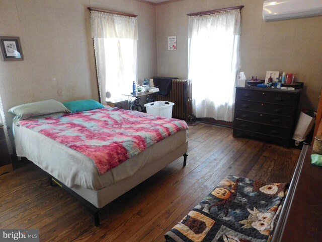 bedroom with radiator, an AC wall unit, and hardwood / wood-style floors