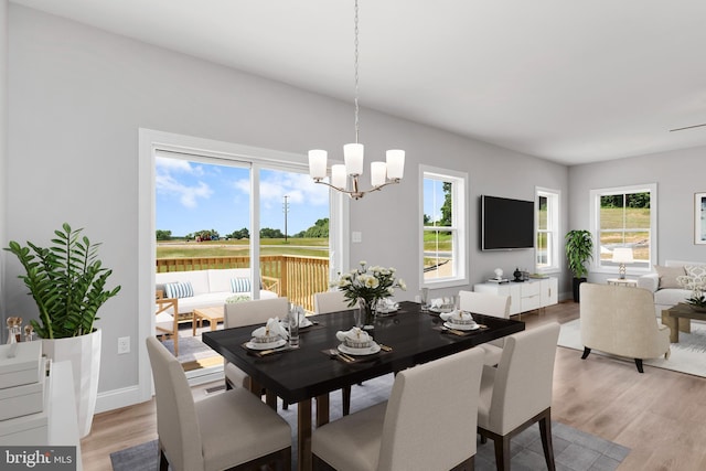 dining room featuring light wood-type flooring, an inviting chandelier, and baseboards