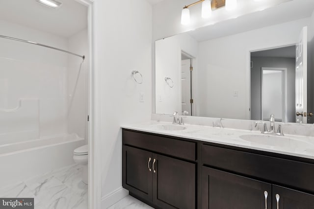 full bathroom with marble finish floor, double vanity, a sink, and toilet