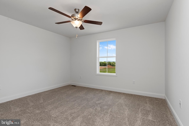 carpeted spare room featuring ceiling fan and baseboards