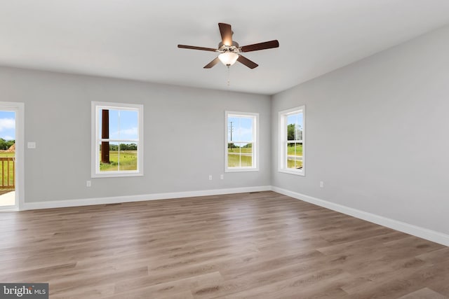 spare room featuring a ceiling fan, a healthy amount of sunlight, baseboards, and wood finished floors