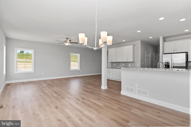 kitchen featuring light wood-style flooring, backsplash, visible vents, and stainless steel refrigerator with ice dispenser