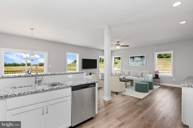 kitchen featuring a sink, white cabinets, open floor plan, stainless steel dishwasher, and decorative backsplash