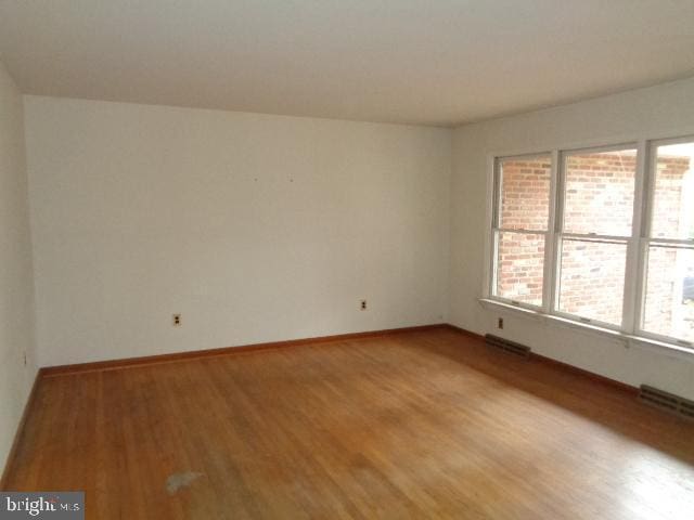 empty room featuring light wood-type flooring, plenty of natural light, visible vents, and baseboards