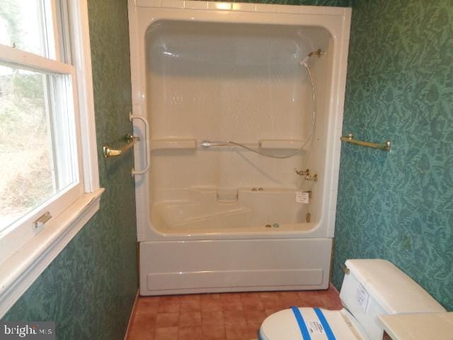 full bathroom with shower / washtub combination, plenty of natural light, toilet, and wallpapered walls