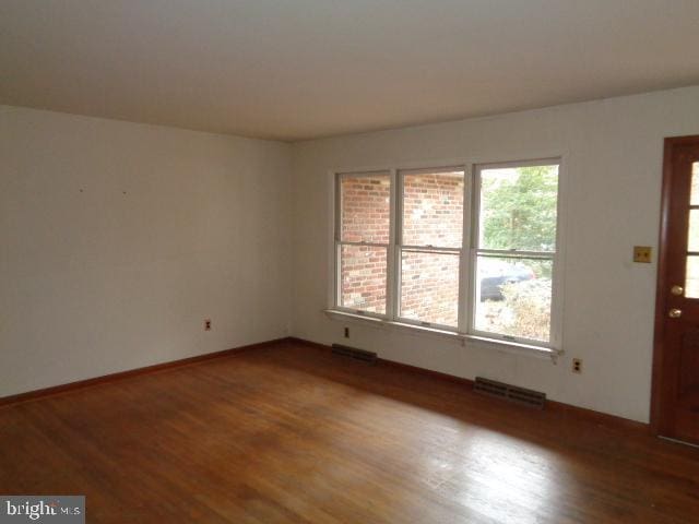 spare room featuring baseboards, visible vents, and wood finished floors