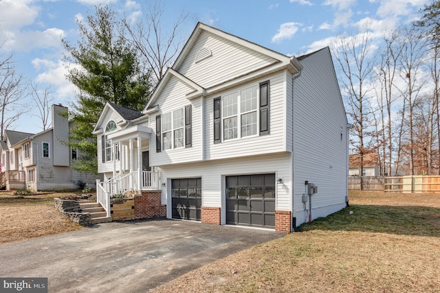 view of front of property with a front lawn, driveway, fence, a garage, and brick siding