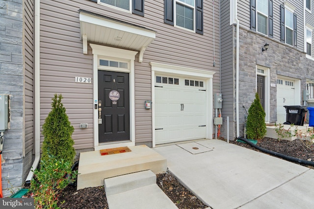 view of exterior entry with a garage and stone siding