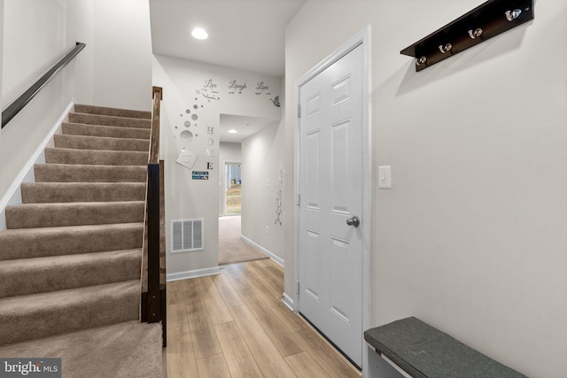 stairway featuring baseboards, visible vents, wood finished floors, and recessed lighting