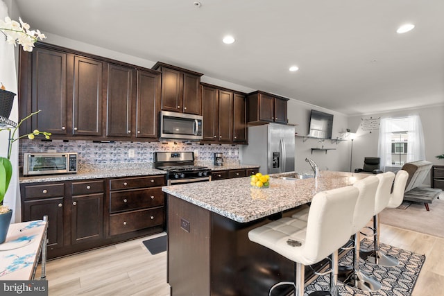 kitchen featuring a toaster, a sink, a kitchen breakfast bar, appliances with stainless steel finishes, and backsplash