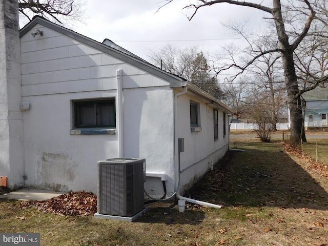 view of side of property with cooling unit and stucco siding