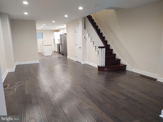 unfurnished living room featuring visible vents, stairway, dark wood-style flooring, a sink, and recessed lighting