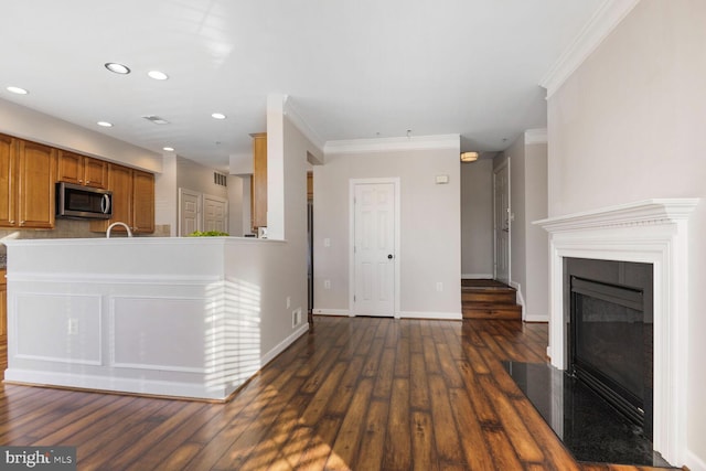 kitchen with stainless steel microwave, baseboards, dark wood-style floors, brown cabinetry, and a glass covered fireplace