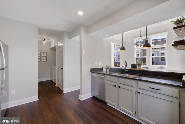 kitchen featuring washer / dryer, baseboards, appliances with stainless steel finishes, dark wood-style flooring, and a sink