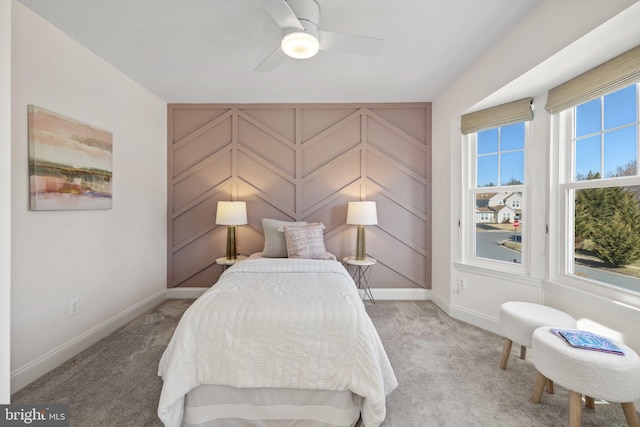 bedroom featuring a ceiling fan, light colored carpet, a decorative wall, and baseboards