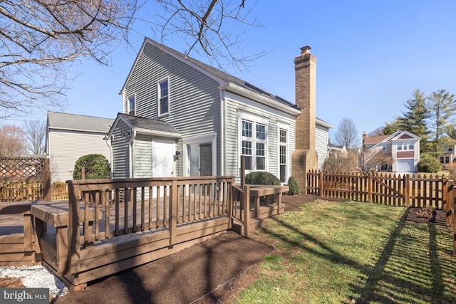 rear view of property featuring a chimney, fence, a deck, and a yard